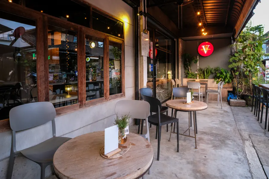 The front terrace in early evening light, tables set under the red V · Vermut Café, Pai Walking Street