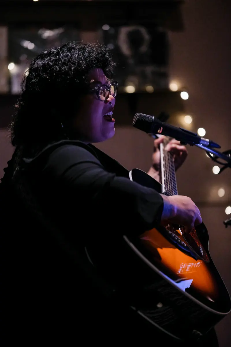 A singer with a guitar, mid-song, under the fairy lights · Vermut Café, Pai Walking Street