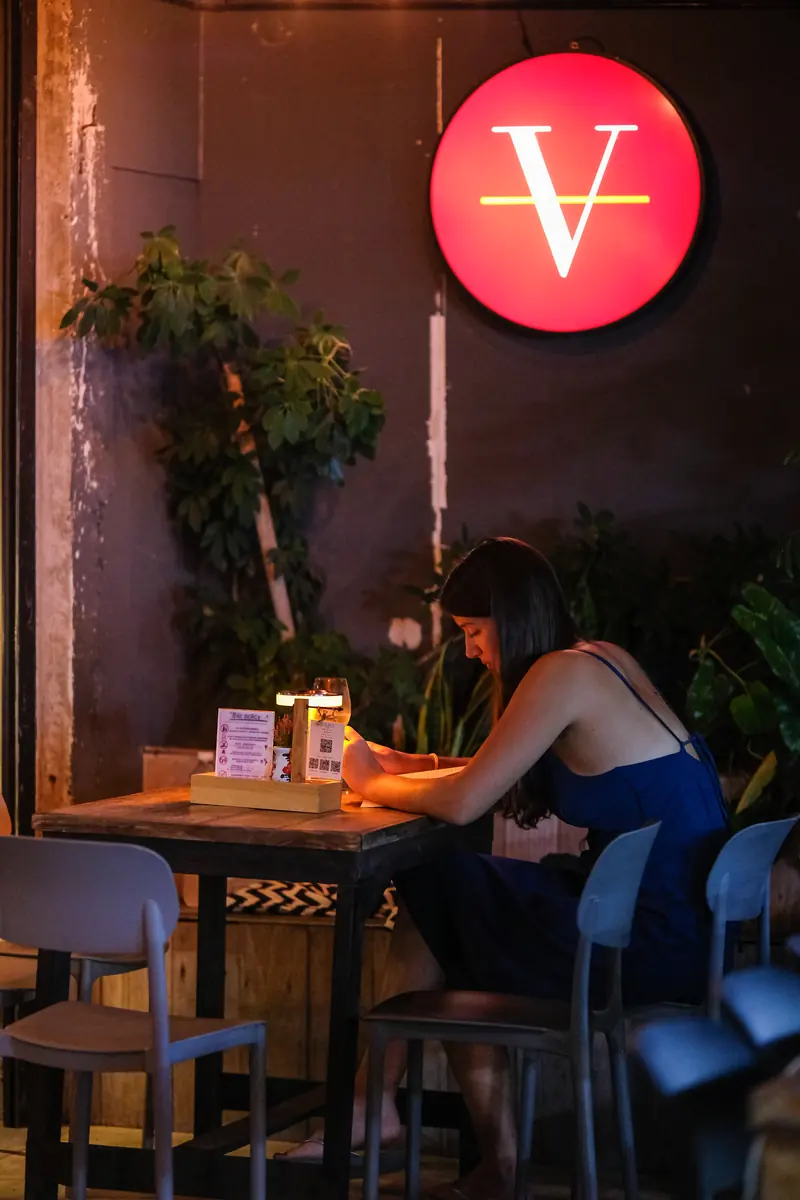 A guest reading the menu under the red V sign at Vermut Café, Pai