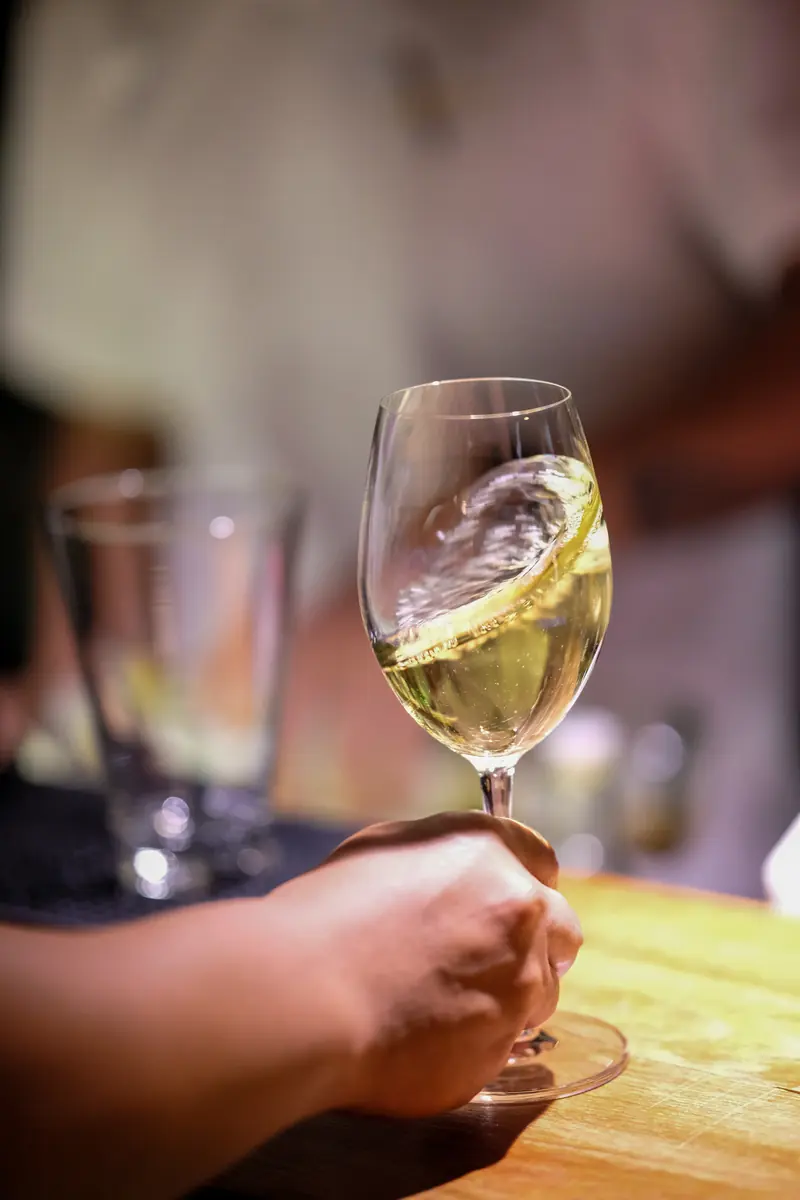 A glass of white wine held up to the light · Vermut Café, רחוב ההליכה בפאי