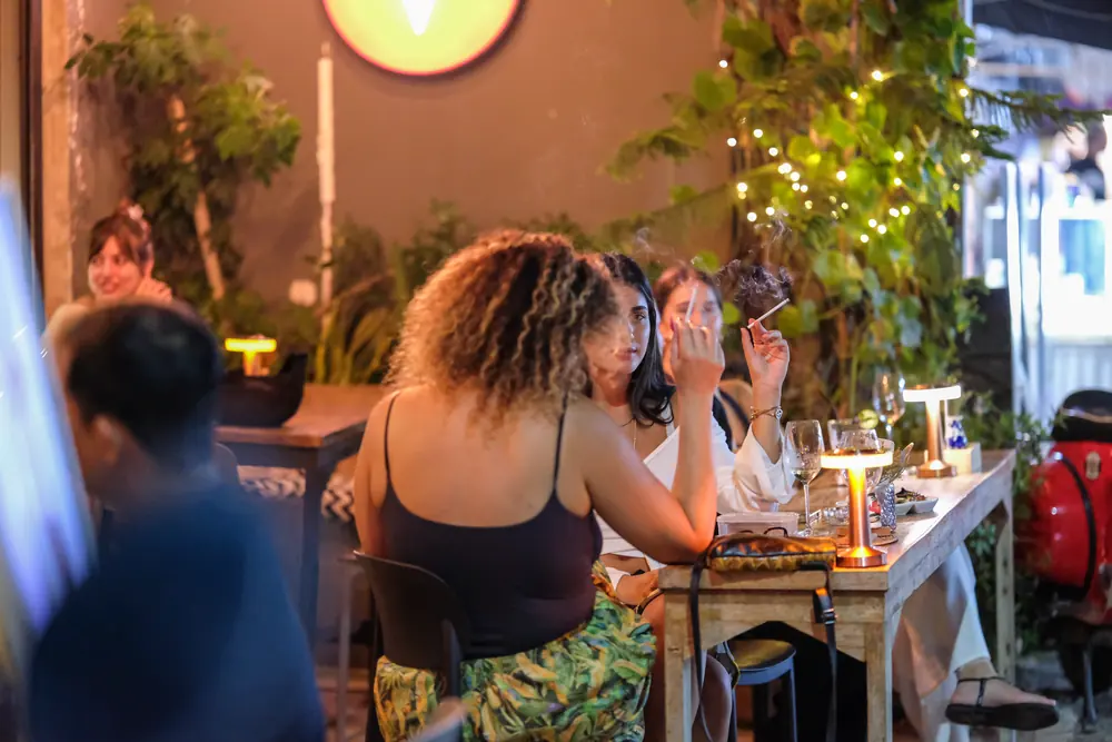 A table of friends out front, plants and lamps around them · Vermut Café, Pai Walking Street