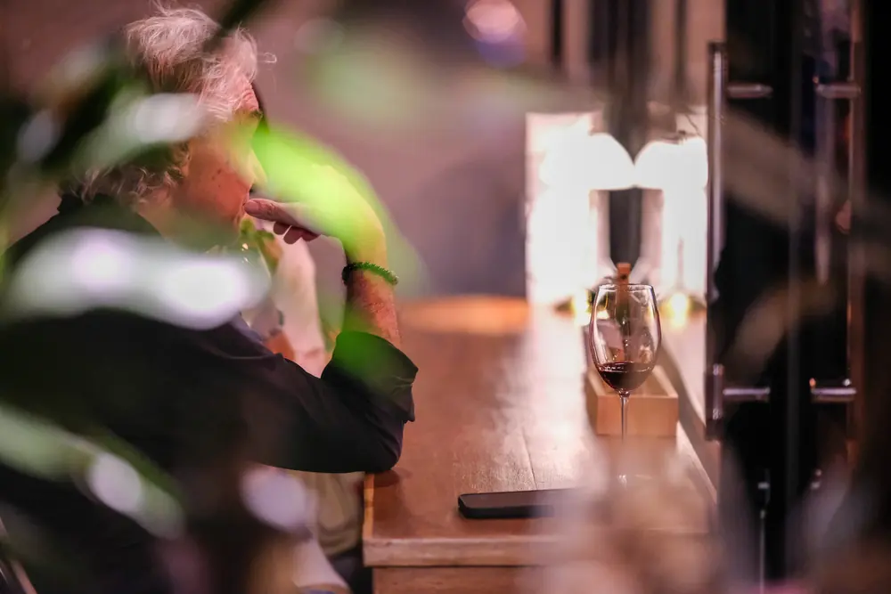 A guest at the front table at night, the lamp lit · Vermut Café, Pai Walking Street