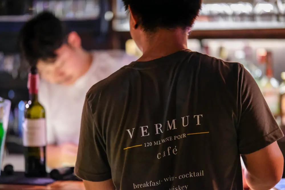 The back of a Vermut café team shirt behind the counter · Vermut Café, Pai Walking Street