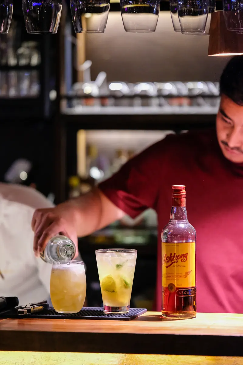 Pouring the drink, a colleague smiling behind · Vermut Café, Pai Walking Street