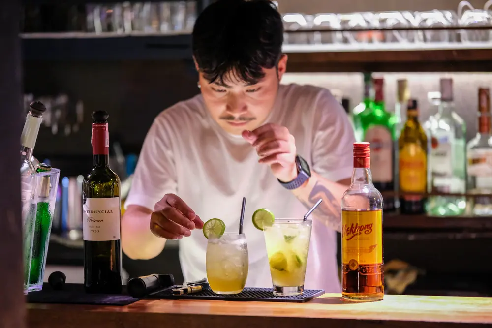 The bartender setting lime on two fresh drinks · Vermut Café, Pai Walking Street