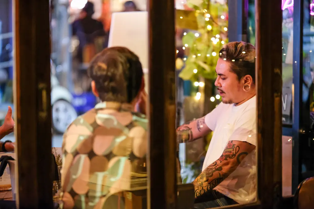 A guest chatting with the bartender across the counter · Vermut Café, Pai Walking Street