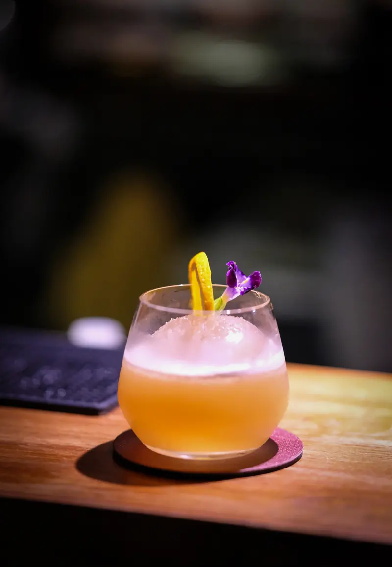 An orange cocktail with a straw on the counter · Vermut Café, Pai Walking Street