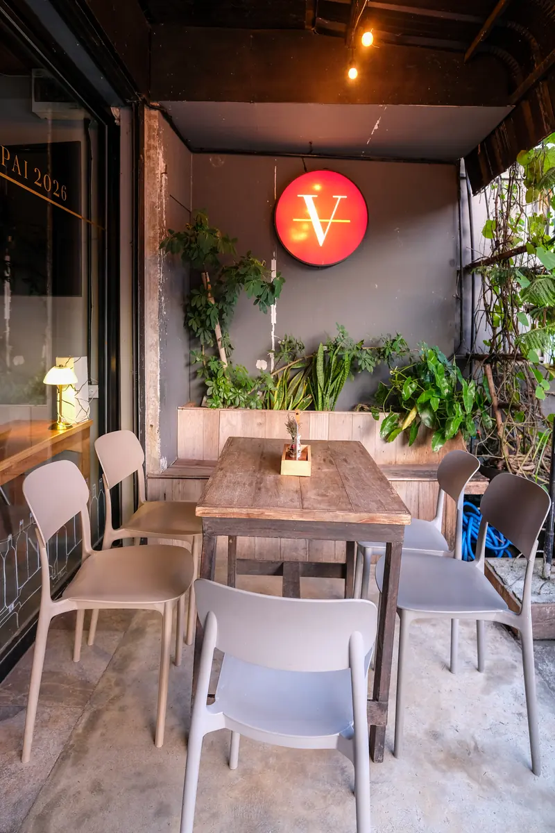 A terrace table and chairs under the red V · Vermut Café, Pai Walking Street