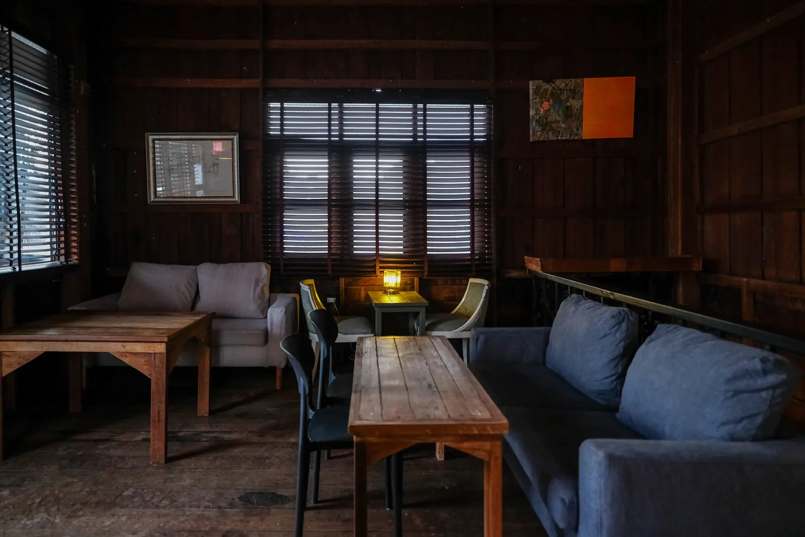 Upstairs in the wooden room — sofas, a low wooden table and lamps by the shutters · Vermut Café, רחוב ההליכה בפאי