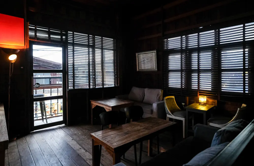 A sofa and table by the shutters upstairs, the street lights outside · Vermut Café, Pai Walking Street