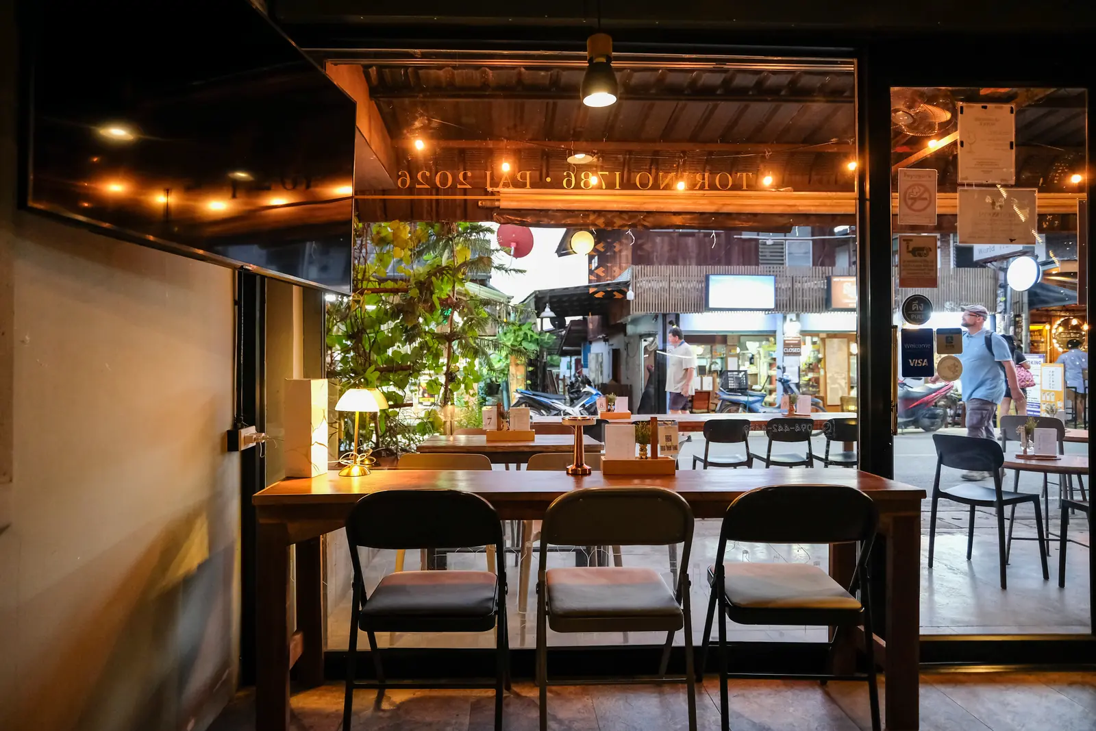 The ground-floor long table by the open glass doors, the walking street outside · Vermut Café, Pai Walking Street