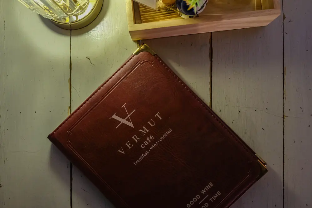 The leather menu cover with the V and the Vermut café wordmark · Vermut Café, Pai Walking Street