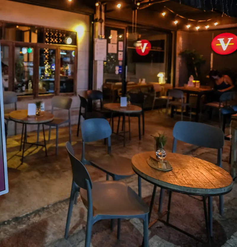 Terrace tables under the string lights, the red V above · Vermut Café, Pai Walking Street