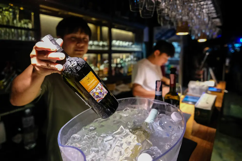 A bottle lifted from the ice, dripping · Vermut Café, רחוב ההליכה בפאי