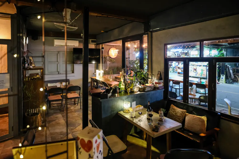 The ground floor at night — plants by the door, the street lit outside · Vermut Café, Pai Walking Street
