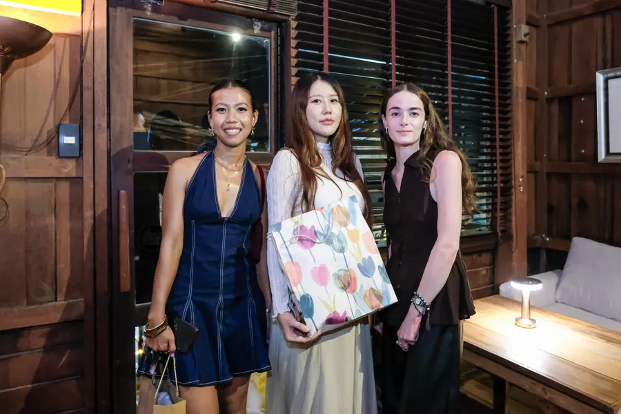 Three friends upstairs by the lamp, one holding a gift · Vermut Café, רחוב ההליכה בפאי