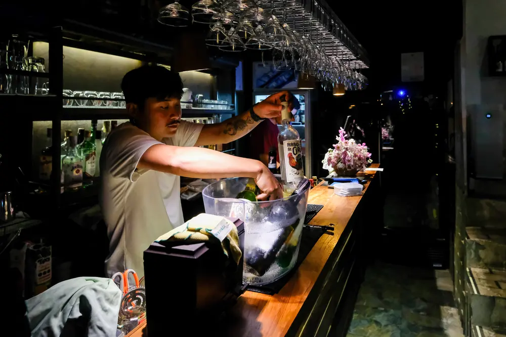 The bartender lifting a bottle from the ice bucket · Vermut Café, רחוב ההליכה בפאי