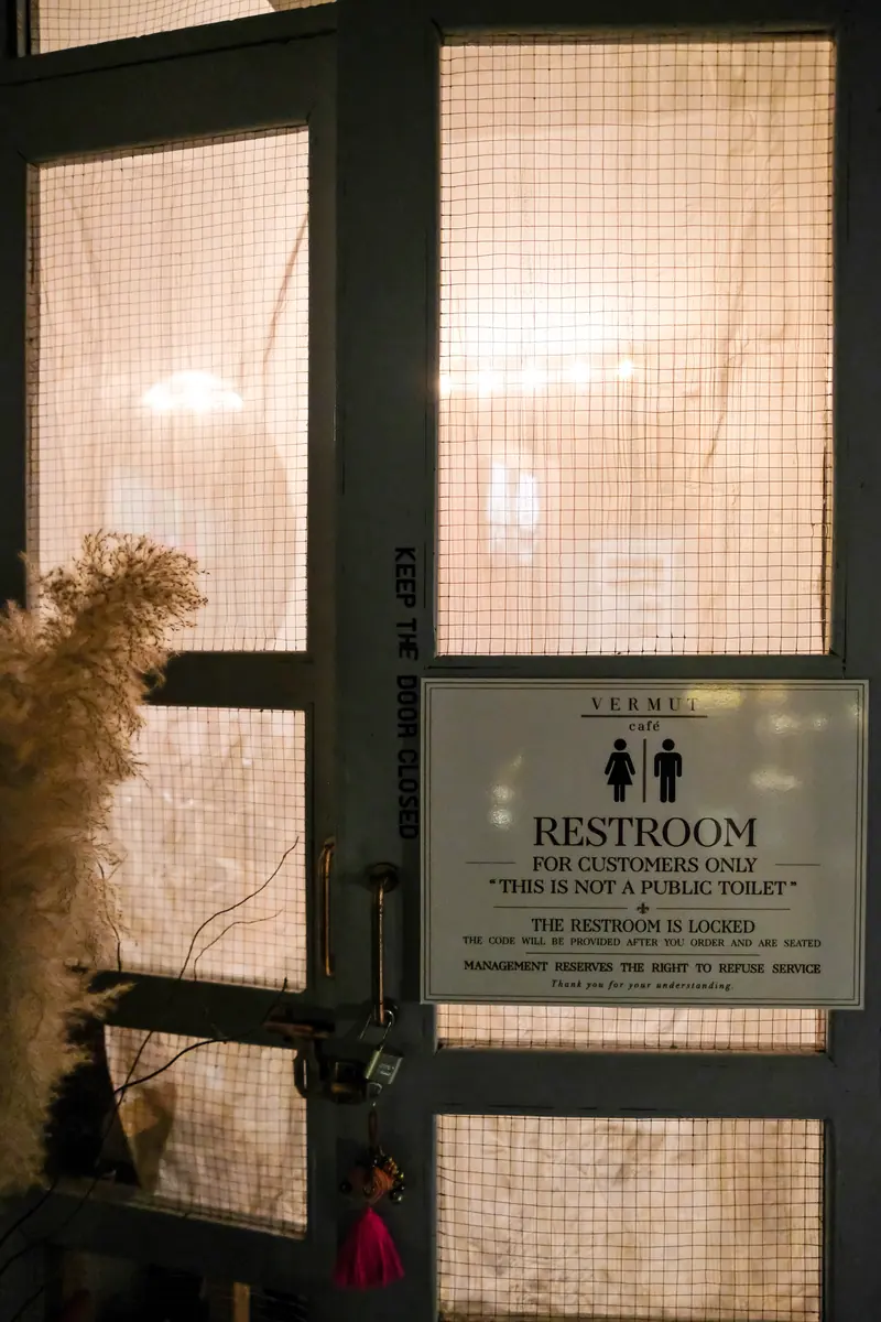 The frosted glass door to the restroom, a dried flower beside it · Vermut Café, Pai Walking Street